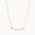 gold necklace with wavy curve pendant on white background