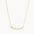 gold necklace with wavy curve pendant on white background