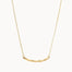 gold necklace with wavy curve pendant on white background