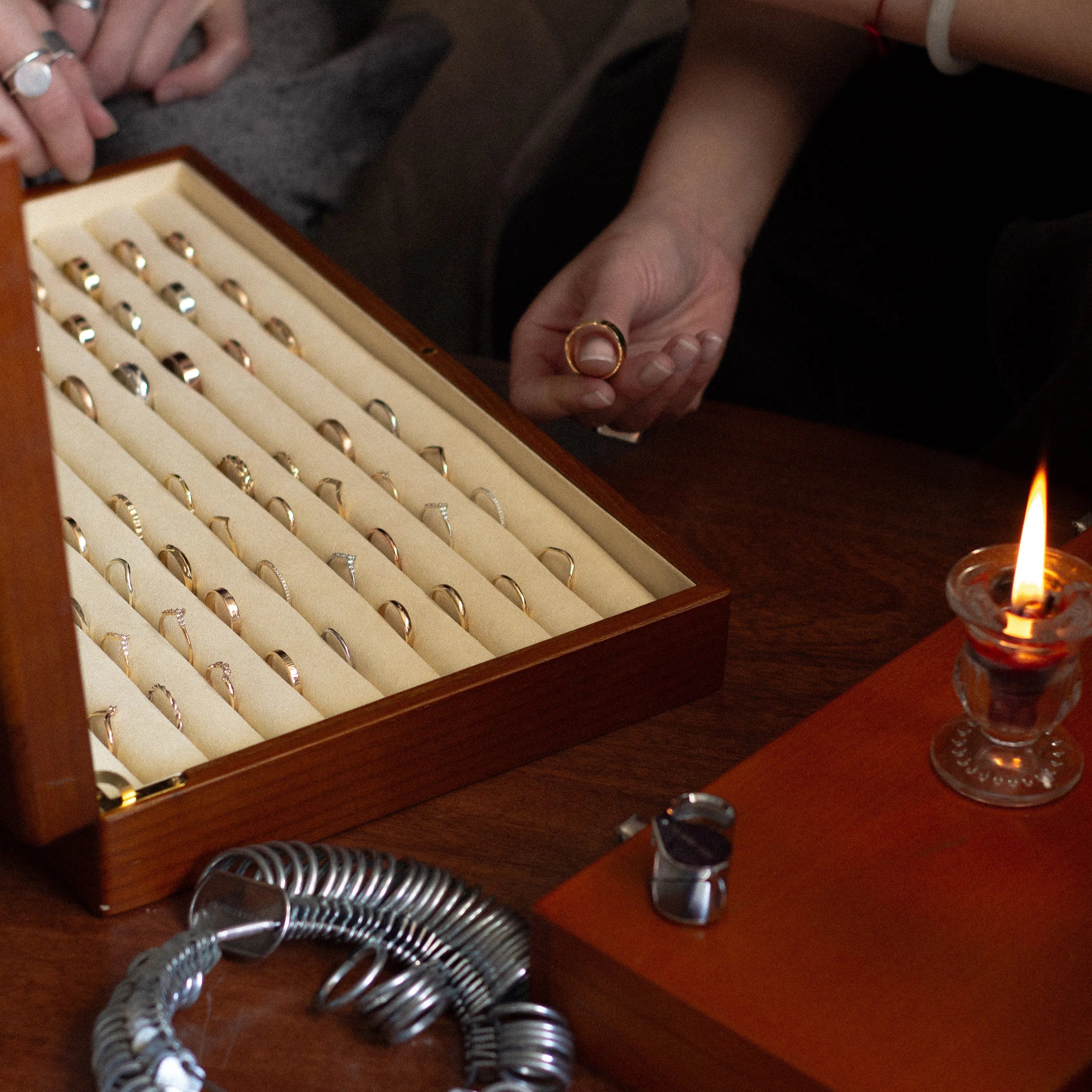 Jewelry box with rings on a table next to a lit candle and flowers