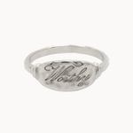 A silver signet ring with a textured oval face featuring the engraved script word 'Worthy', shown on a plain white background.
