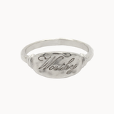 A silver signet ring with a textured oval face featuring the engraved script word 'Worthy', shown on a plain white background.