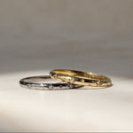 Two gold rings on a textured surface with a neutral background