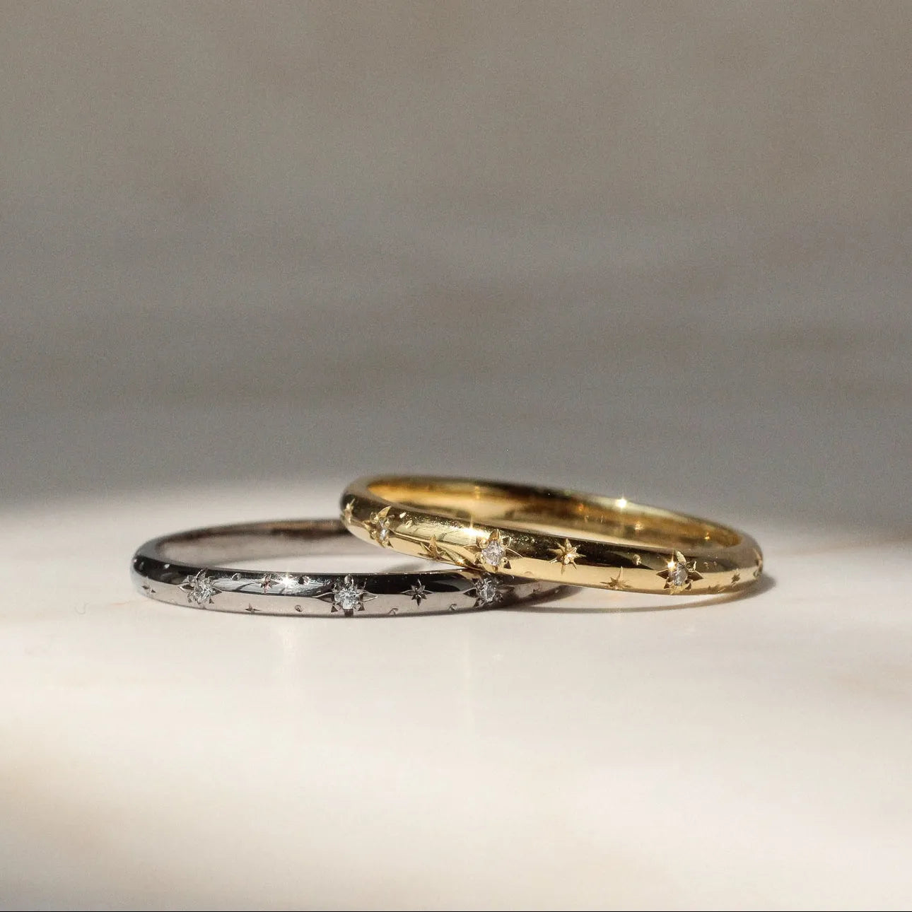 Two gold rings on a textured surface with a neutral background