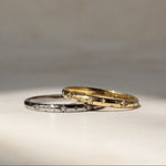 Two gold rings on a textured surface with a neutral background