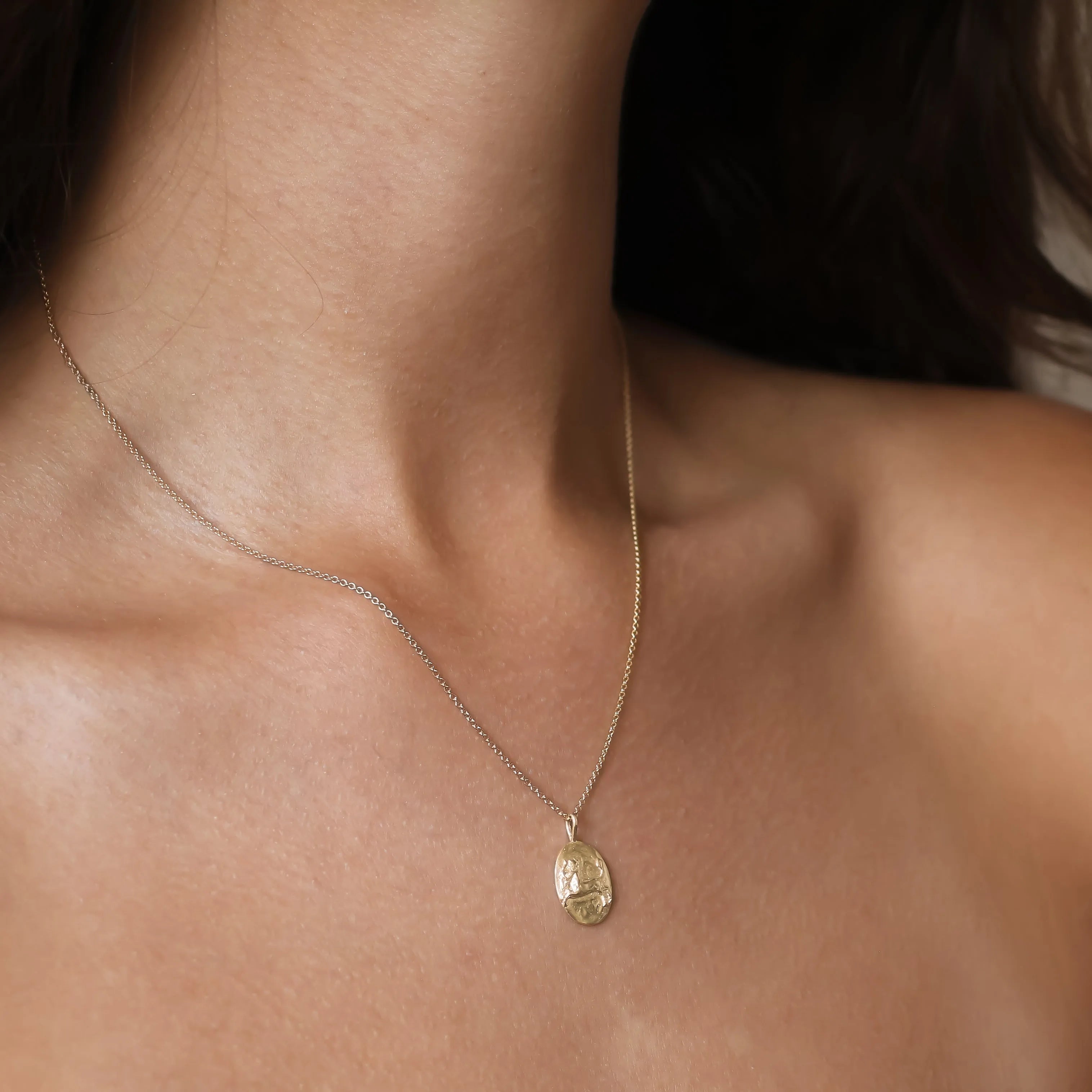 close up of a gold oval pendant sagittarius necklace worn on a models neck