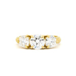 A yellow gold three-stone ring featuring a large round center diamond flanked by two smaller round diamonds, set in a classic prong setting against a plain white background.
