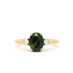 A yellow gold ring featuring an oval dark green sapphire in the center, flanked by two small round diamonds on either side of the band, set against a plain white background.