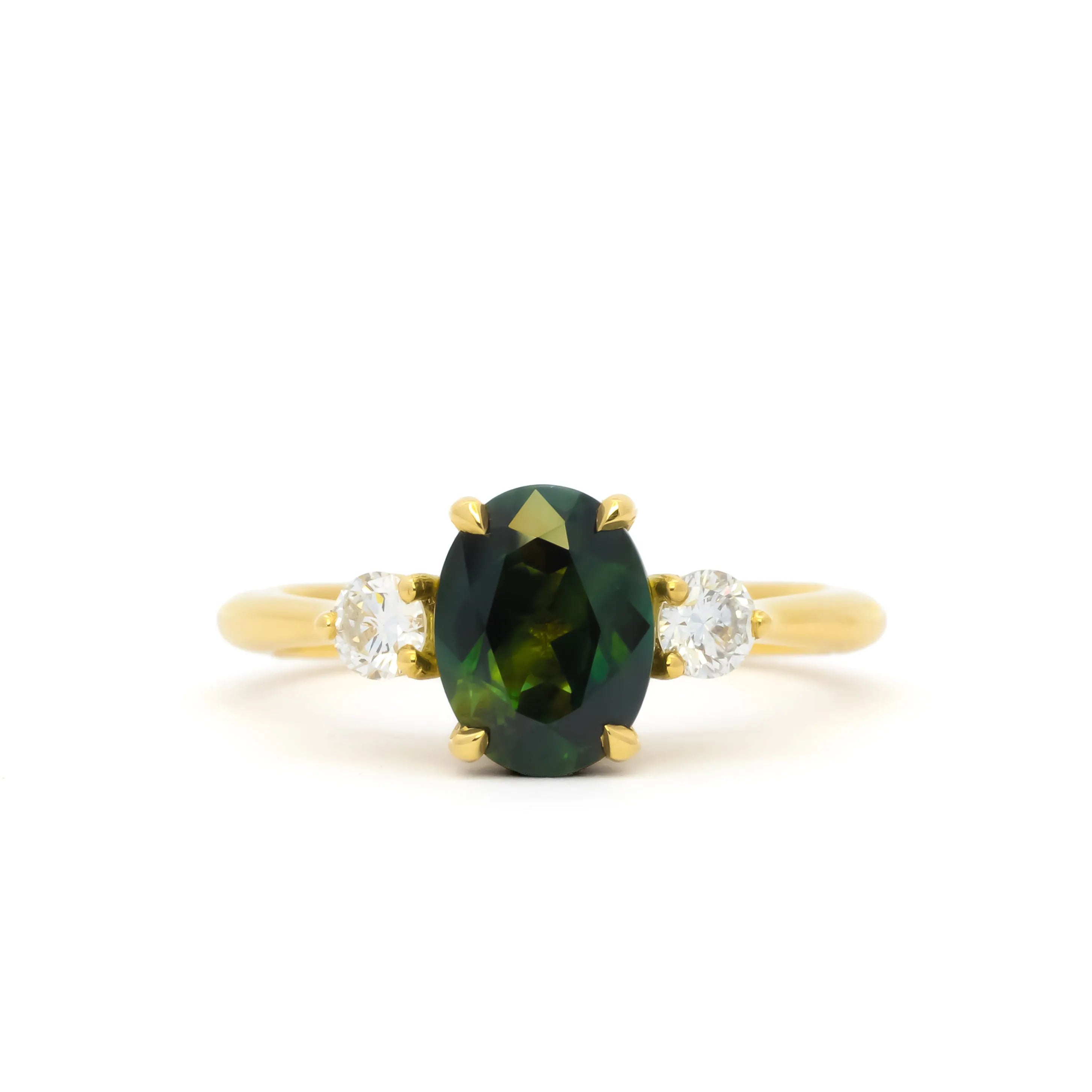A yellow gold ring featuring an oval dark green sapphire in the center, flanked by two small round diamonds on either side of the band, set against a plain white background.