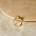 side view of a yellow diamond engagement ring with claws resting against a marbled ceramic tray