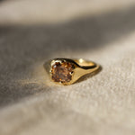 asscher cut brown diamond engagement ring resting on a beige fabric