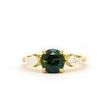 engagement ring with round green gemstone and kite-shaped diamonds on a white background