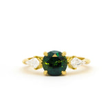 engagement ring with round green gemstone and kite-shaped diamonds on a white background