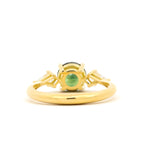 A yellow gold ring with a central round green gemstone and small side stones, shown on a plain white background.