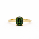 Gold ring with a green gemstone on a white background
