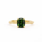 Gold ring with a green gemstone on a white background