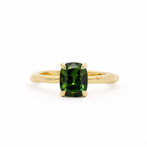 Gold ring with a green gemstone on a white background