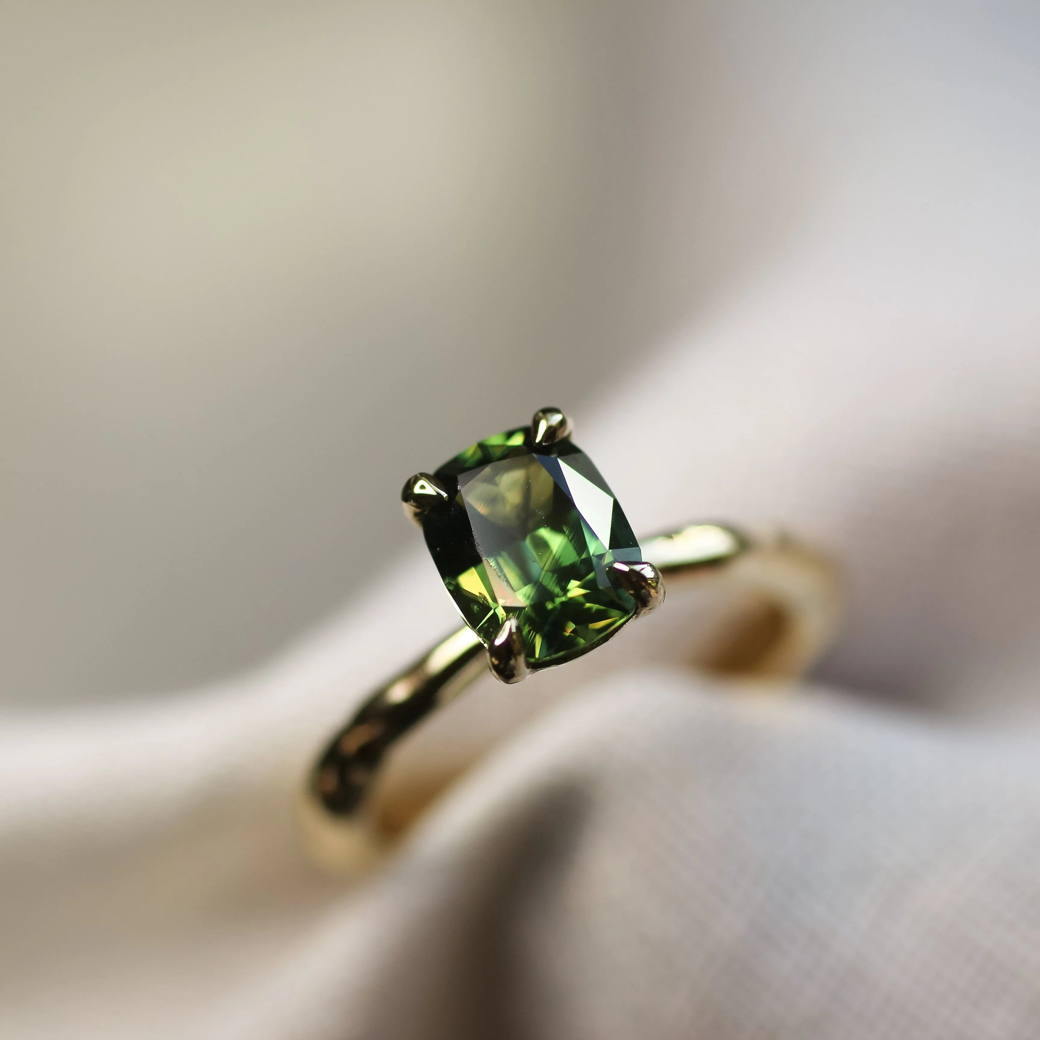 green solitaire engagement ring with blurred background