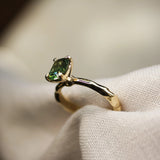 green solitaire sapphire ring with organic textured gold band in neutral fabric