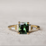 Gold ring with a green gemstone on a textured surface