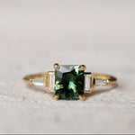 Gold ring with a green gemstone on a textured surface