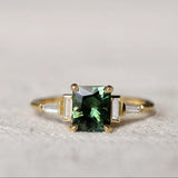 Gold ring with a green gemstone on a textured surface