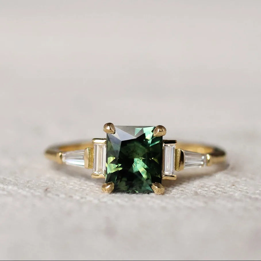 Gold ring with a green gemstone on a textured surface