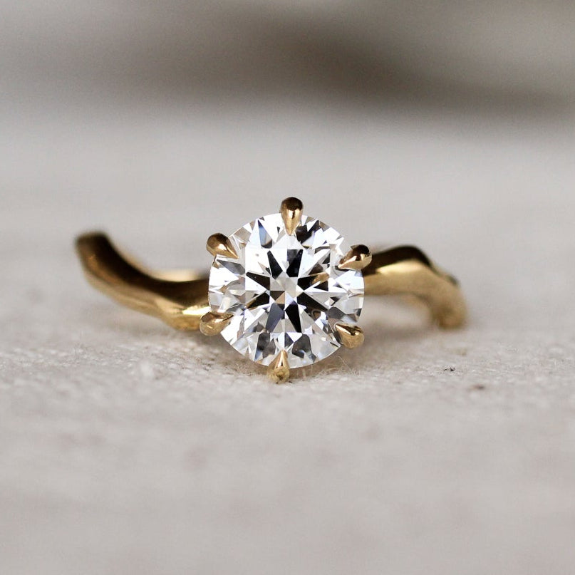 Gold ring with a diamond and wavy organic band on a light surface