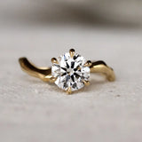 Gold ring with a diamond and wavy organic band on a light surface