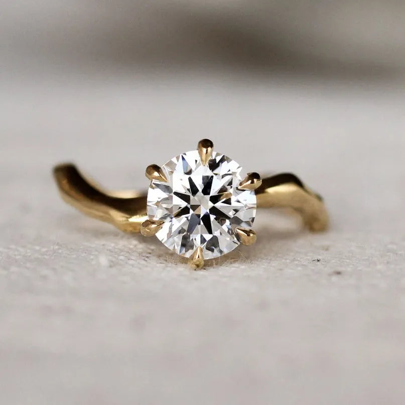 Gold ring with a diamond and wavy organic band on a light surface