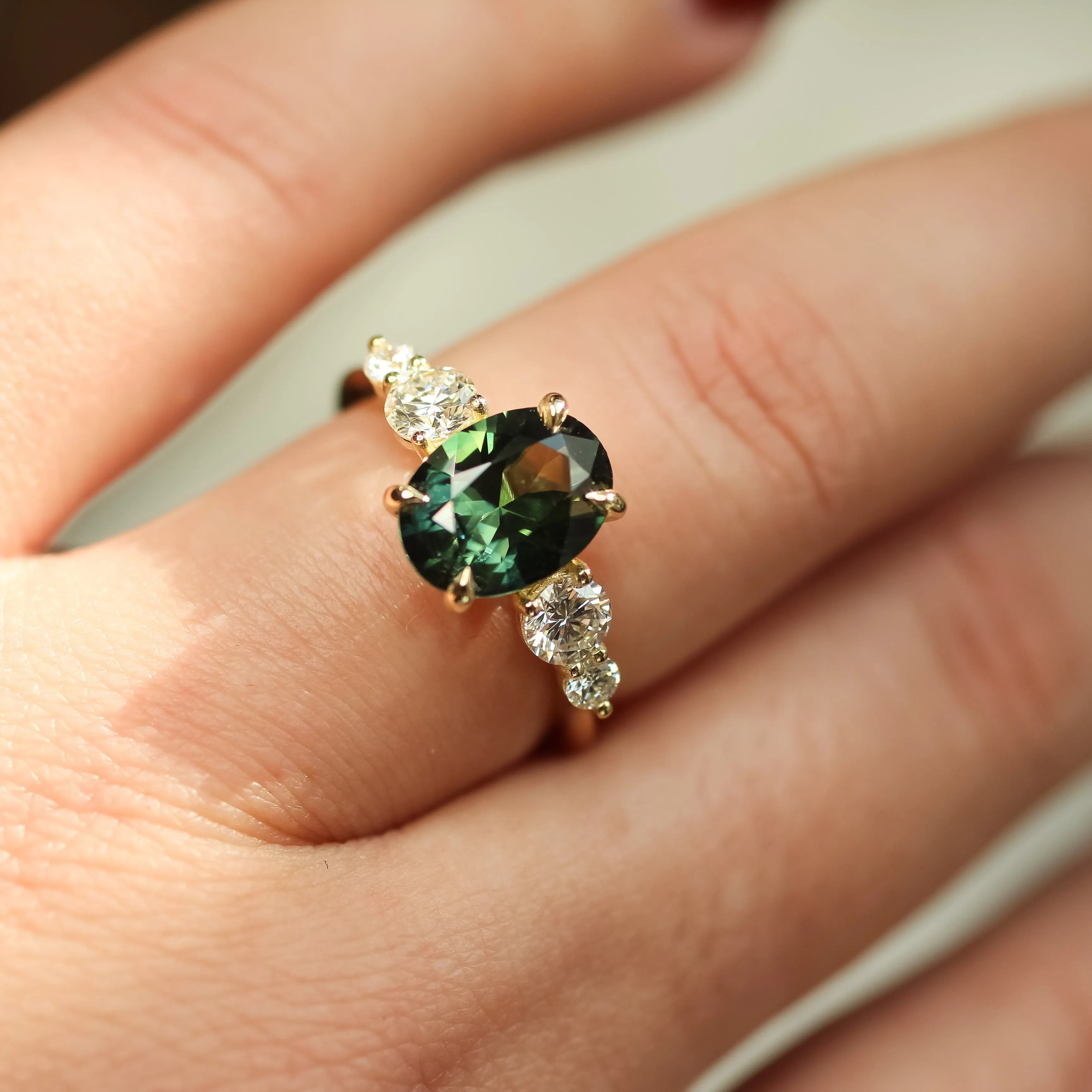hand wearing large 2ct green sapphire ring with 4 diamonds