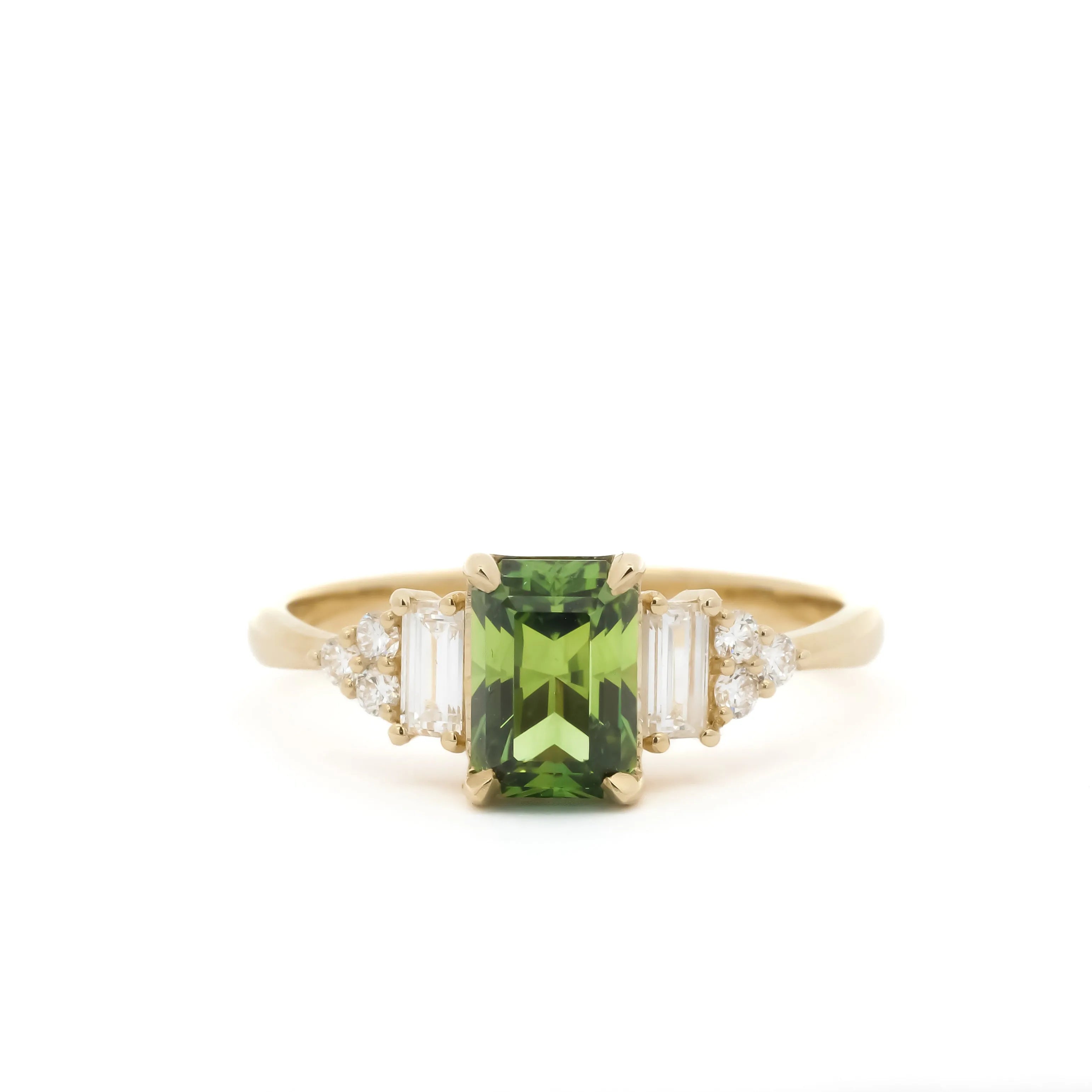 Gold ring with a green gemstone and diamond accents on a white background
