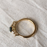 top view displaying high-set collet of pear sapphire and diamond engagement ring on a beige fabric