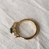 top view displaying high-set collet of pear sapphire and diamond engagement ring on a beige fabric