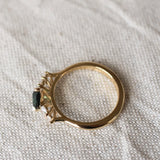 top view displaying high-set collet of pear sapphire and diamond engagement ring on a beige fabric