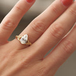 Gold ring with a diamond on a hand with red nail polish against a blurred background