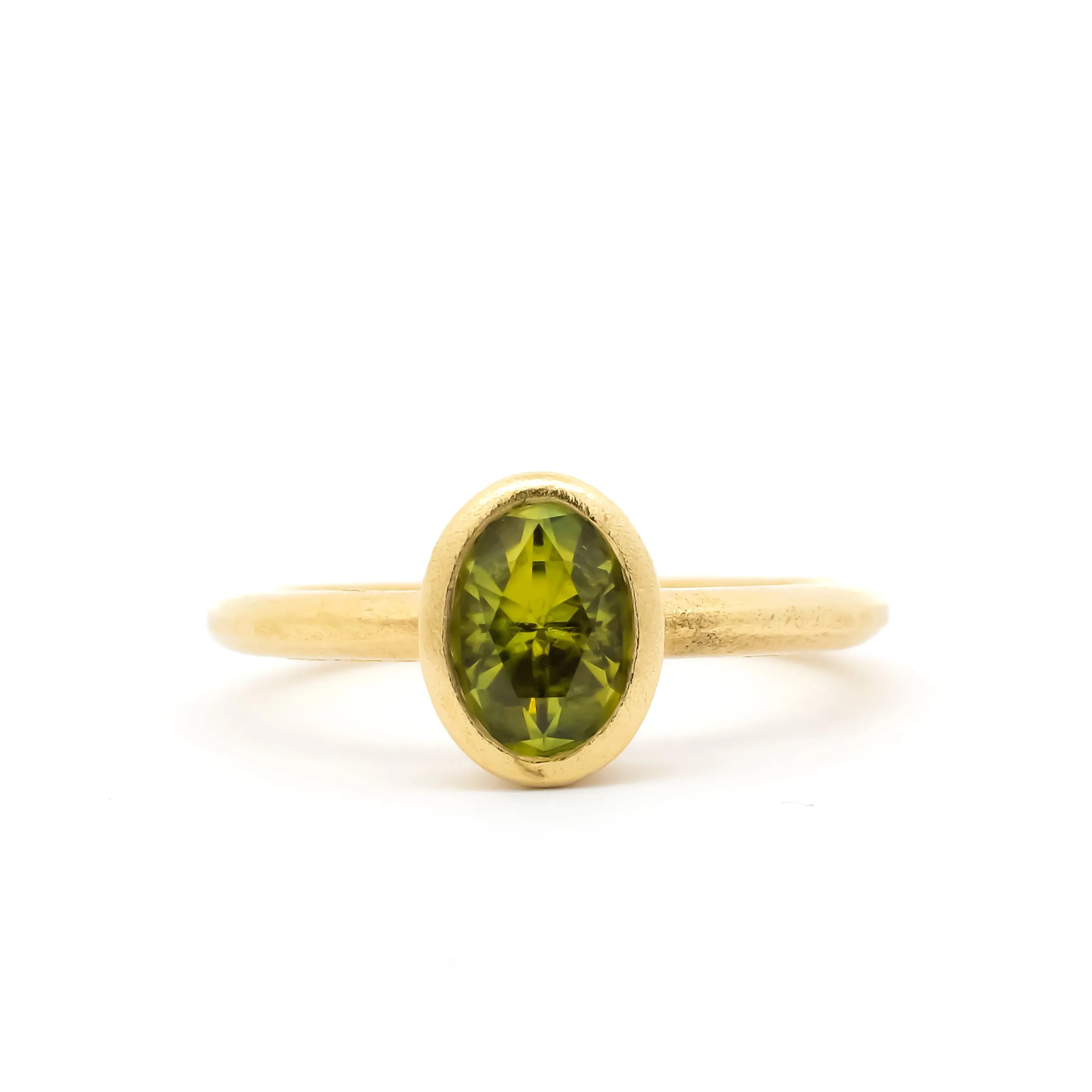 bezel set engagement ring with green yellow sapphire and satin finish on a white background
