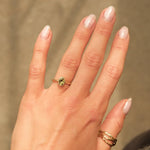 hand wearing oval green sapphire bezel engagement ring with shadows