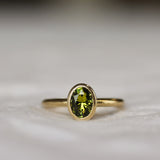 Bezel Solitaire Green/Yellow Sapphire Engagement Ring with Satin Finish on a neutral fabric