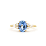 Gold ring with a blue gemstone and diamond accents on a white background