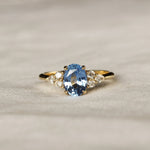 Gold ring with a blue gemstone on a textured beige surface