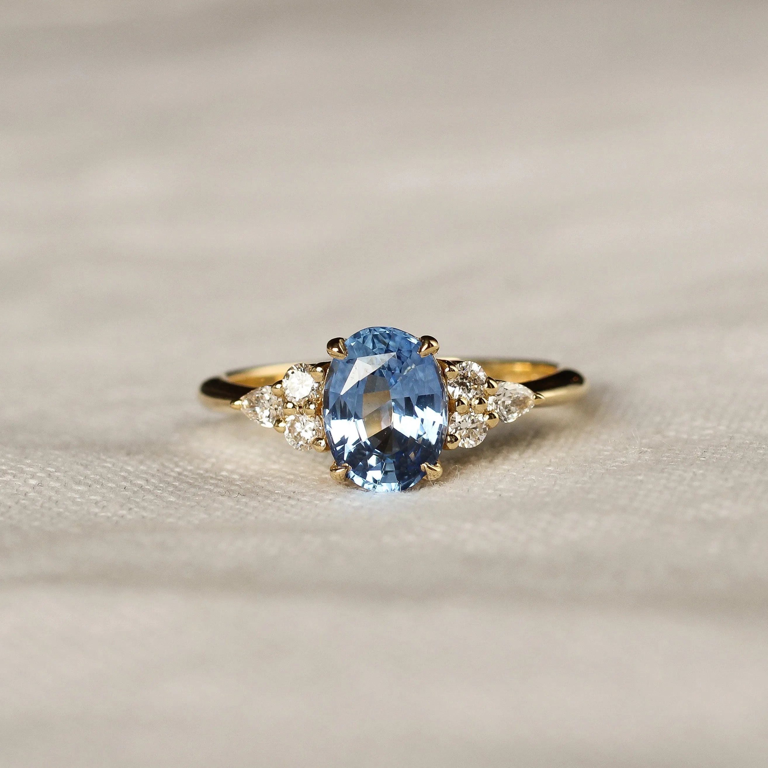 Gold ring with a blue gemstone on a textured beige surface