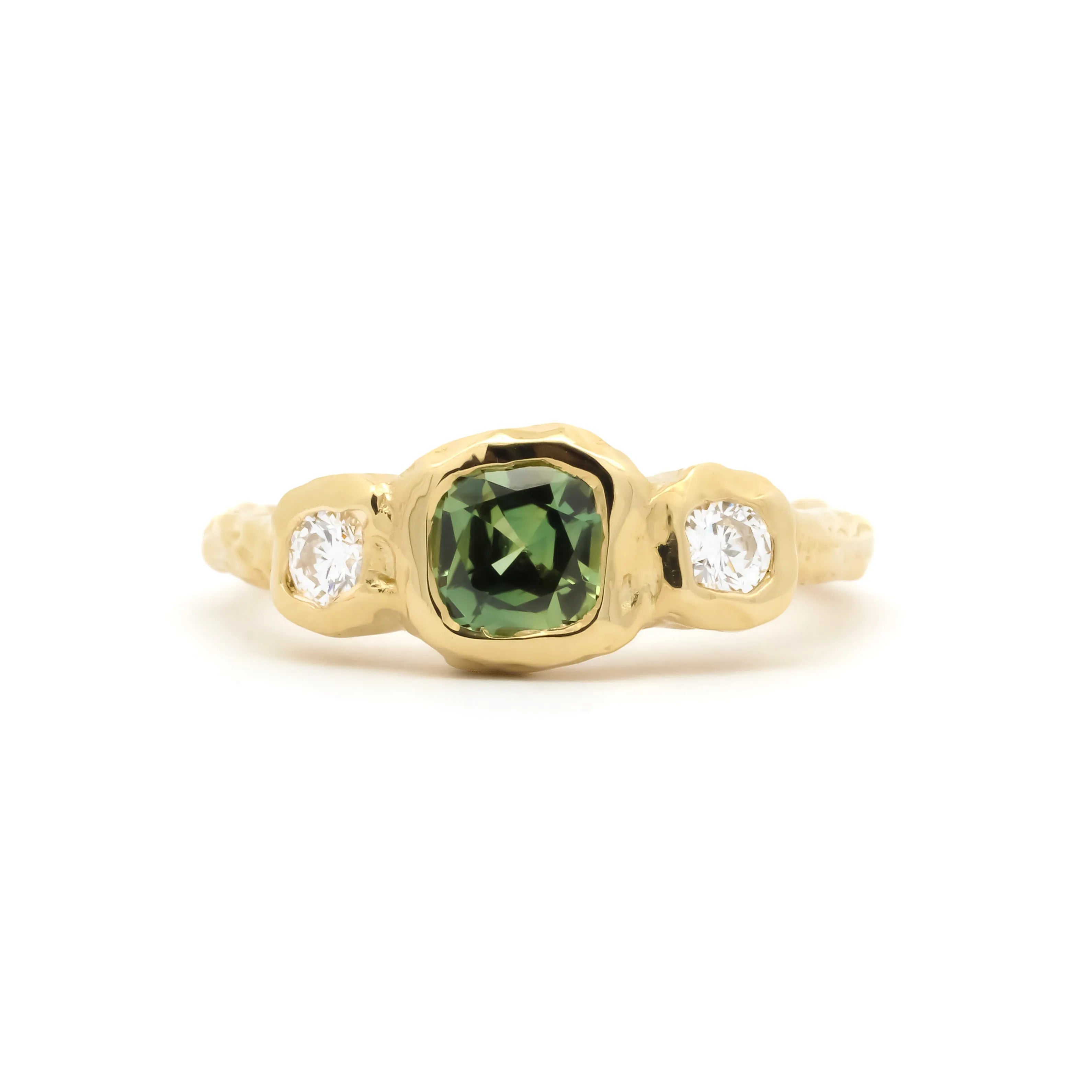 molten bezel engagement ring with cushion cut green sapphire and round diamonds on a white background