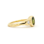 Gold molten organic textured ring with a green gemstone and diamond on a white background