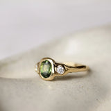 Oval Green Sapphire and Diamond Molten Organic Engagement Ring on a ceramic surface