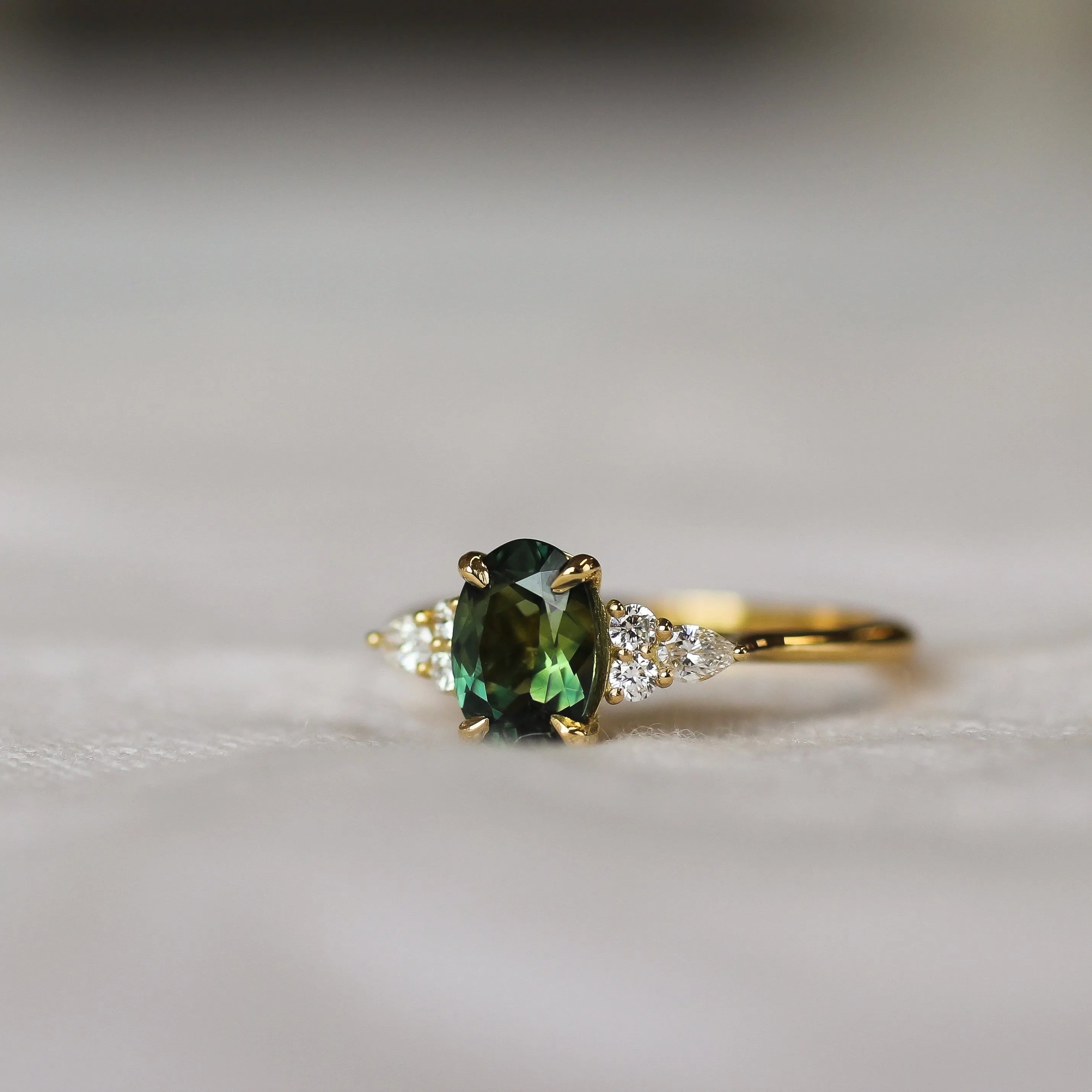 Gold ring with a green gemstone on a light background