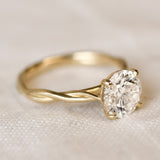 Gold ring with a diamond on a beige fabric background