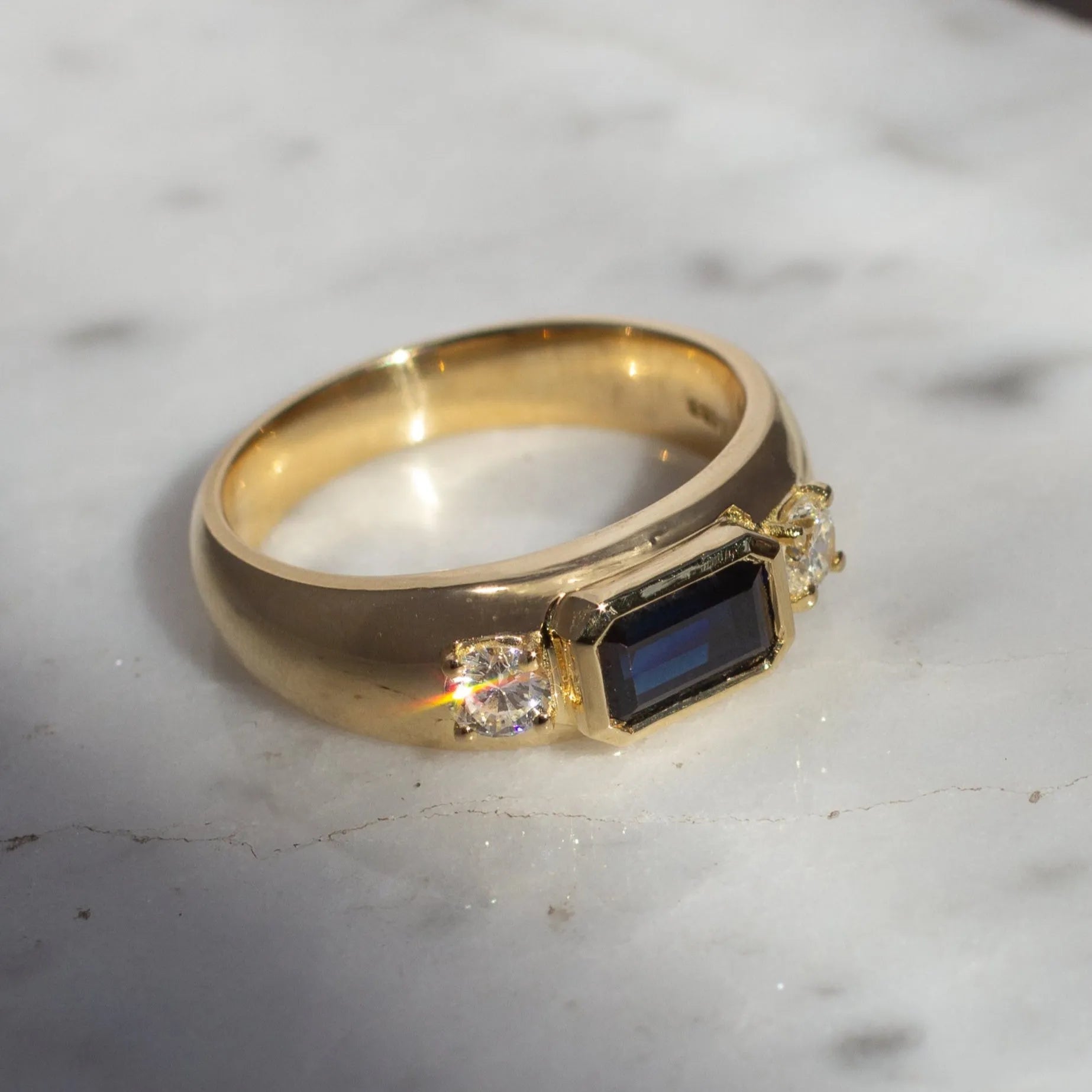 chunky gold bespoke ring with emerald cut sapphire and round diamonds 