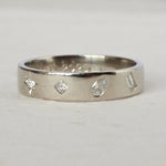 Silver ring with diamond-shaped cutouts on a light gray background