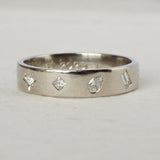 Silver ring with diamond-shaped cutouts on a light gray background
